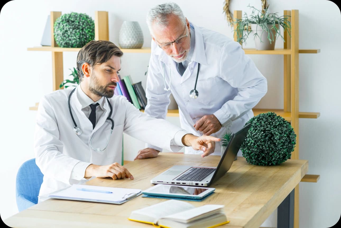 Licensed healthcare providers collaborating around a laptop